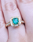 A 14k yellow gold emerald ring on a person's finger.