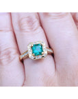 A 14k yellow gold emerald ring on a person's finger.