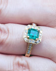 Gold ring with a natural Colombian emerald on a finger.