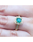 Gold ring with a natural Colombian emerald on a finger.