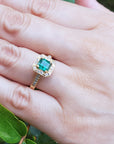A May's birthstone emerald ring for women on a hand against a natural background.