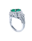 18K white gold engagement ring with a vibrant emerald, diamond halo, and baguette side diamonds.