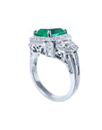 18K white gold engagement ring with a vibrant emerald, diamond halo, and baguette side diamonds.