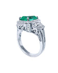 18K white gold engagement ring with a vibrant emerald, diamond halo, and baguette side diamonds.