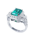 Vibrant 2.47 ct. emerald engagement ring in 18K white gold with diamond halo and baguette side diamonds.