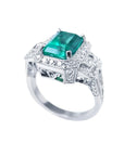 Vibrant 2.47 ct. emerald engagement ring in 18K white gold with diamond halo and baguette side diamonds.