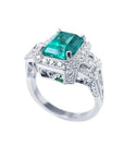 Vibrant 2.47 ct. emerald engagement ring in 18K white gold with diamond halo and baguette side diamonds.