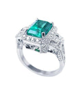 Vibrant 2.47 ct. emerald engagement ring in 18K white gold with diamond halo and baguette side diamonds.