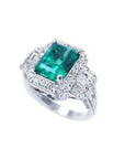 Vibrant 2.47 ct emerald engagement ring in 18K white gold with diamond halo and baguette side diamonds.