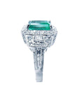 Vibrant 2.47 ct. emerald engagement ring in 18K white gold with diamond halo and baguette side diamonds.