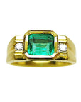 A 14k gold ring for men with a natural colombian emerald bezel set and two side diamonds.