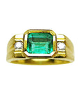 A 14k gold ring for men with a natural colombian emerald bezel set and two side diamonds.