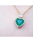 Heart-shaped emerald pendant with diamond halo and round diamond accent on an 18k gold chain.