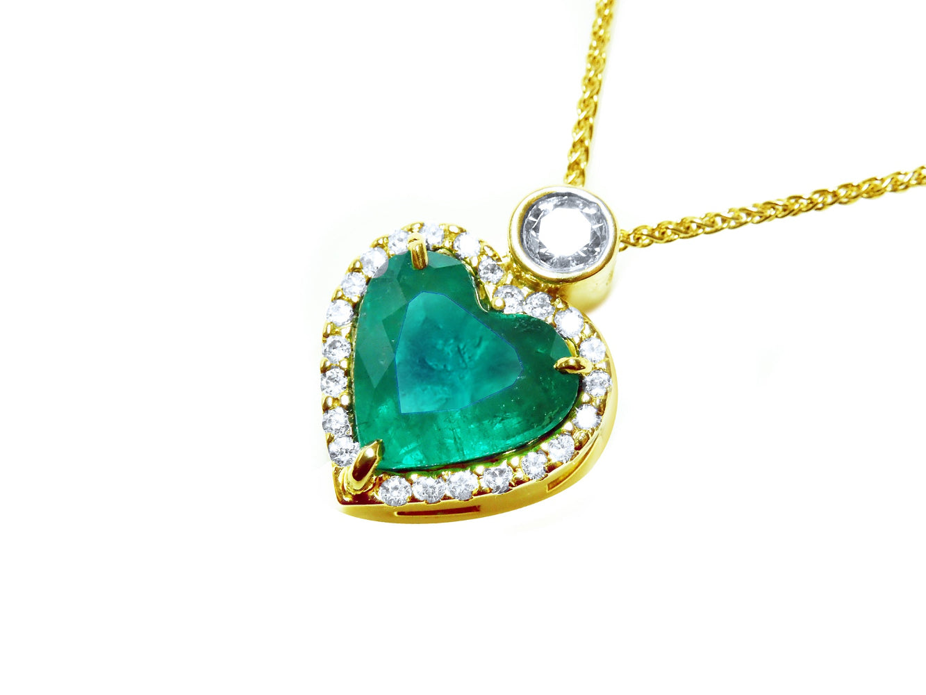 Gold necklace with a heart-shaped emerald and diamond pendant on a left side profile view.
