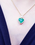 Heart-shaped emerald pendant necklace on a person chest with a blue garment.