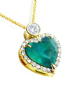 Heart-shaped natural Colombian emerald pendant with gold border and small halo diamond, topside view.