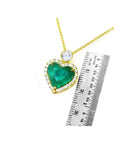18k gold heart pendant with a large bluish-green emerald, halo diamonds, and a delicate gold chain.