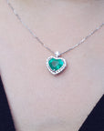 Heart-shaped emerald pendant on a white gold chain on a person's neck