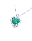 Natural emerald heart pendant in 14K white gold, framed by diamonds on a delicate chain.