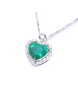 Natural emerald heart pendant in 14K white gold, framed by diamonds on a delicate chain.