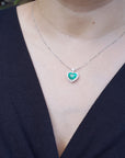 Necklace with a heart-shaped pendant worn by a woman in a dark blue outfit.