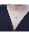 Necklace with a heart-shaped pendant worn by a woman in a dark blue outfit.