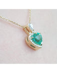 14K yellow gold heart pendant with a medium-deep green emerald and diamond halo on a delicate chain.