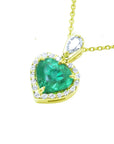 Gold pendant with a heart-shaped emerald and halo diamonds on a white background.