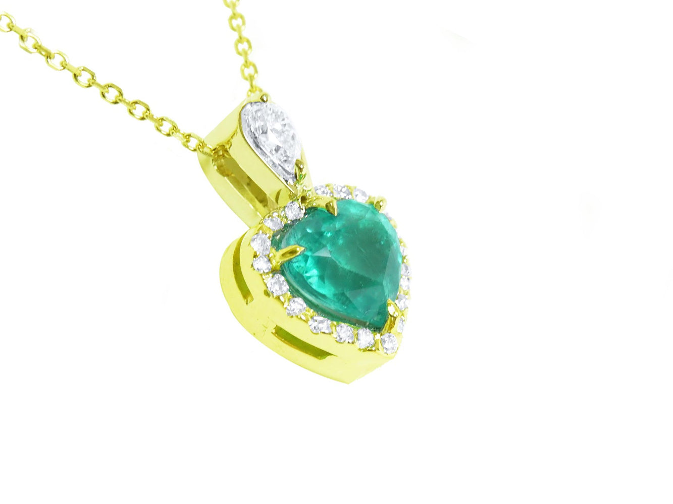 Gold pendant with a heart shaped emerald and diamonds on a white background.
