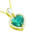 Heart-shaped emerald pendant with gold frame and diamond accents on a topside position view.