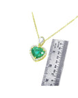 Gold necklace with a heart-shaped emerald pendant next to a ruler for size reference on a white background