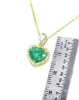 Gold necklace with a heart-shaped emerald pendant next to a ruler for size reference on a white background