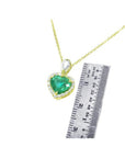 14K yellow gold heart pendant with a deep green emerald and diamond halo, next to a ruler.