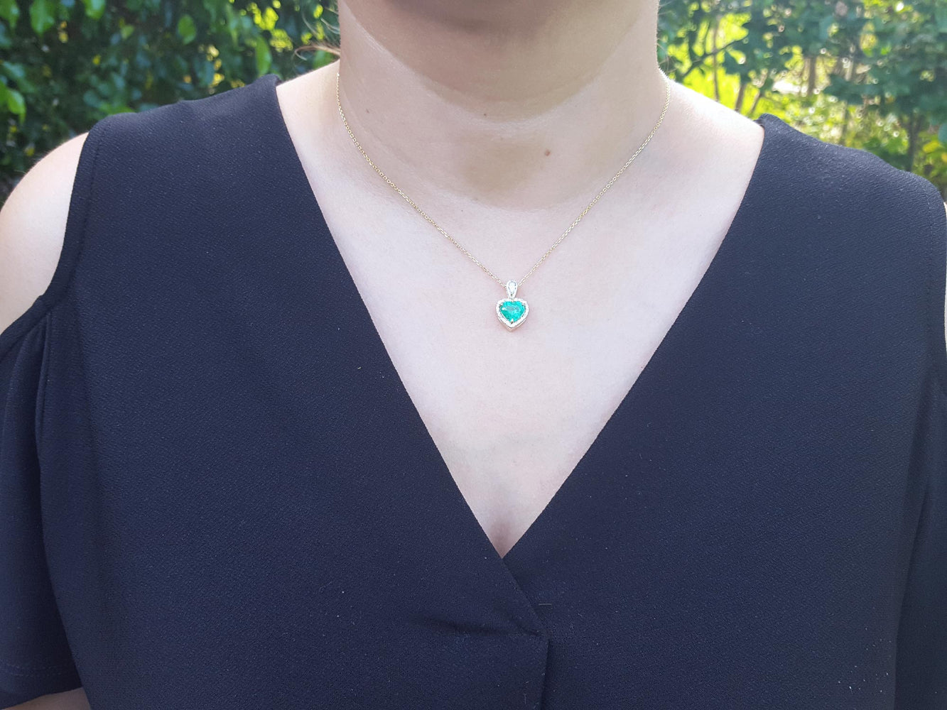 A woman wearing a necklace with a heart-shaped pendant outdoors