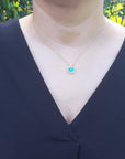 A woman wearing a necklace with a heart-shaped pendant outdoors