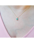 Emerald cut Colombian emerald slider pendant with halo diamonds on a delicate 14K gold chain.