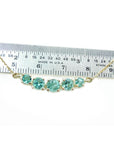 14K gold necklace with five round, medium light green Colombian emeralds, varying in size, displayed against a ruler.