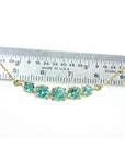14K gold necklace with five round, medium light green Colombian emeralds, varying in size, displayed against a ruler.