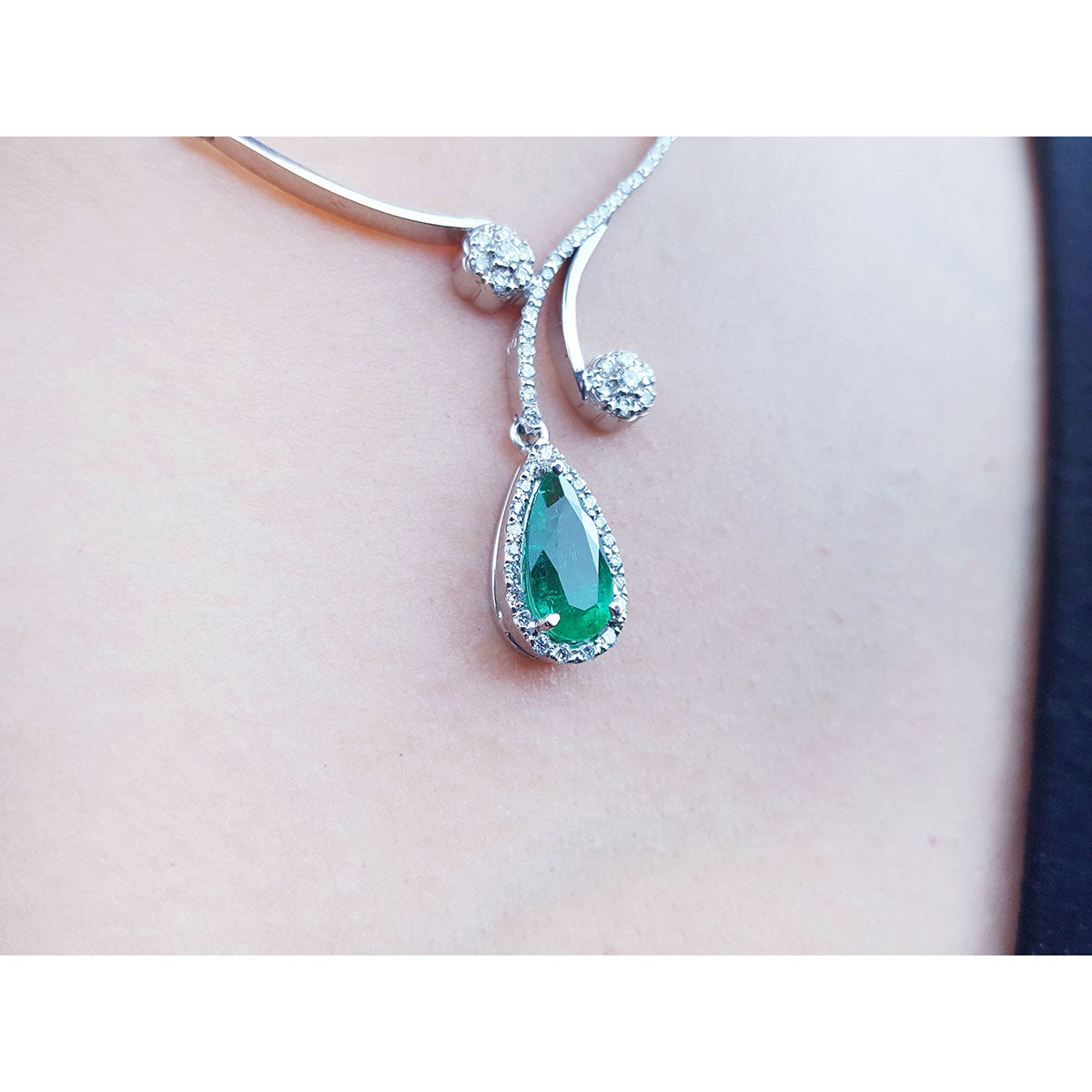 white gold necklace with a teardrop Colombian emerald in a halo diamond pendant on lady's collar