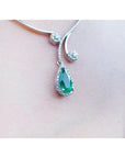white gold necklace with a teardrop Colombian emerald in a halo diamond pendant on lady's collar