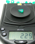2.25 ct. natural pear-cut Muzo mine Colombian emerald on a digital scale, displaying vivid bluish-green color.