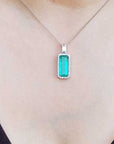 Green emerald pendant on a necklace against a black background