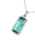 The topside view of a natural emerald pendant with halo diamond on a white background