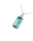 Elongated natural emerald pendant with halo diamonds in 18K white gold.