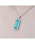 Elongated natural emerald pendant with halo diamonds in 18K white gold on a chain.