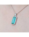 Elongated natural emerald pendant with halo diamonds in 18K white gold on a chain.