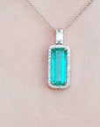 Green emerald pendant necklace on a light pink background