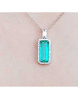 Green emerald pendant necklace on a light pink background