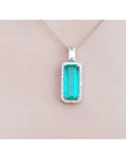 Green emerald pendant necklace on a light pink background