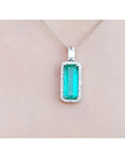 Green emerald pendant necklace on a light pink background